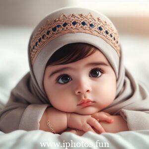 A baby doll in a pink dress and white hat, sitting peacefully on a shelf.