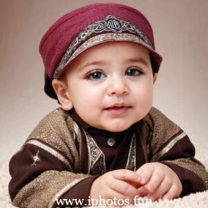 A baby wearing a white headscarf and necklace, looking adorable and innocent